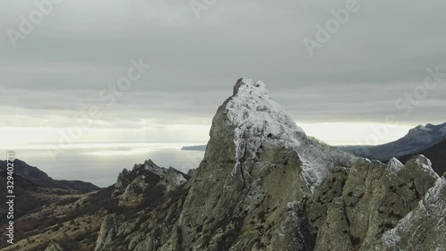 view from above on the mountain range on the sea coast with scant vegetation and snow on an overcast day photo