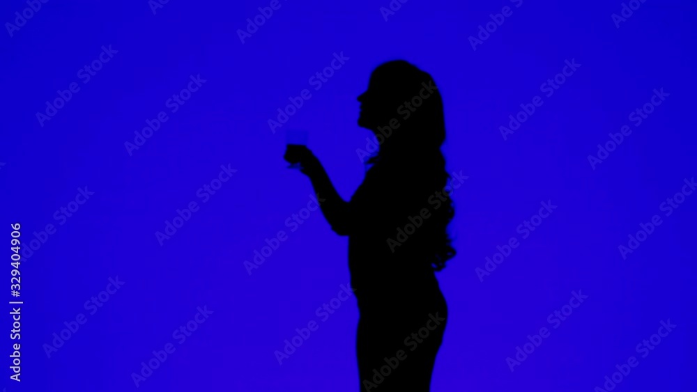 Silhouette of a woman with curly hair drinking wine from a glass on a blue background.