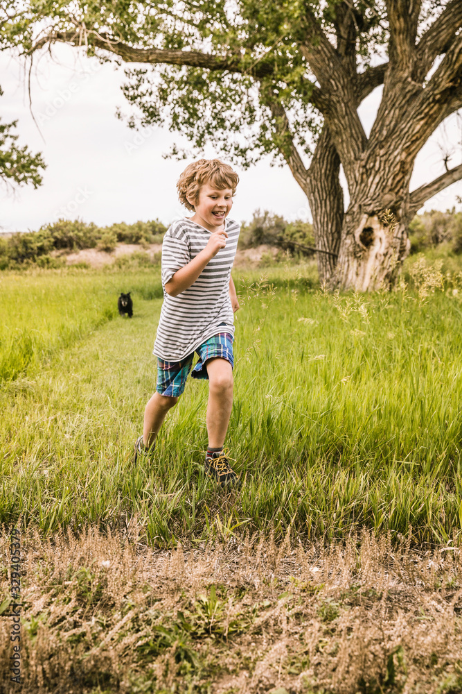 Young boy running through the grass in a park setting. Bridger, Montana, USA Young boy running through the grass in a park setting. Bridger, Montana, USA
