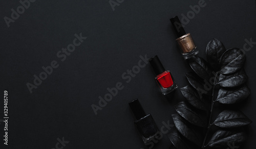 Fototapeta Red, golden and black Nail polish and luxury leaf on a black background with top view and copy space. Minimal black trendy 2020. Cosmetics concept Flatlay.