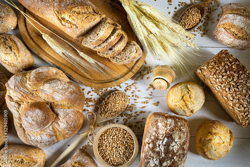 Obraz na płótnie Traditional wheat bread, rolls and ears of cereals on a white wooden background w salonie