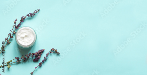 Concept of natural beauty products. With white  cream and lavender flower for skin care on a pastel blue background with green leaves. Top view and copy space Flat lay.