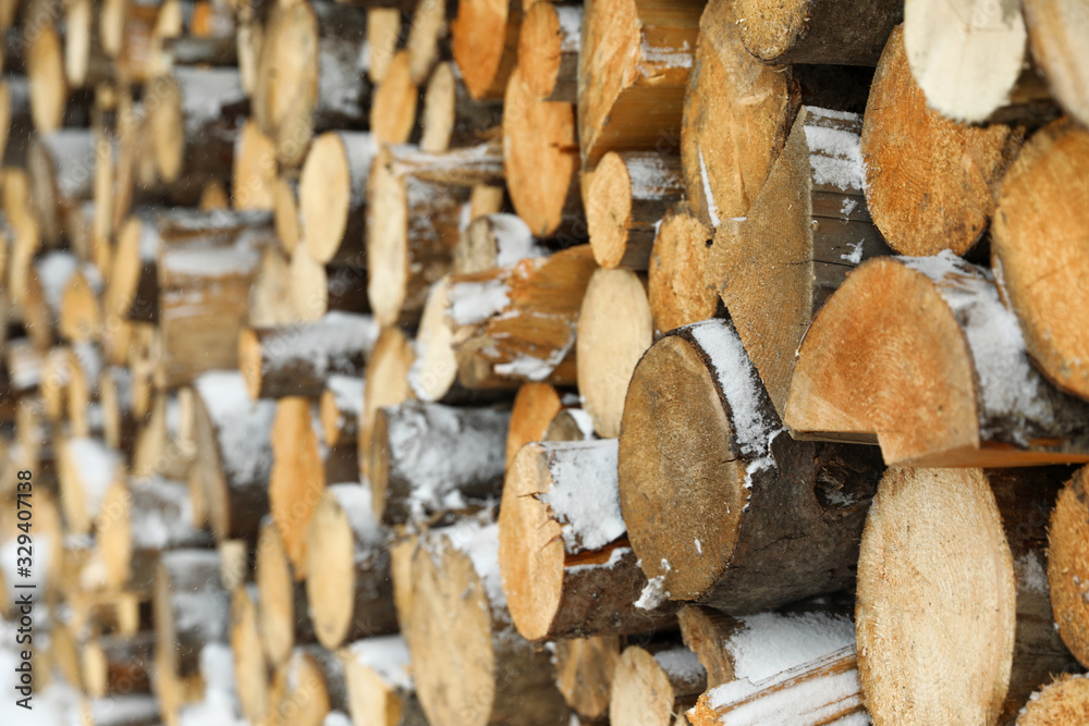 Stacked firewood with snow as background, closeup. Heating house in winter Stacked firewood with snow as background, closeup. Heating house in winter