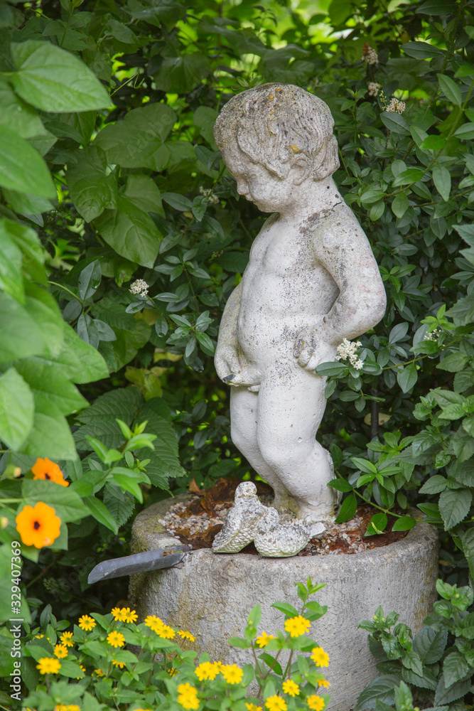 Marmor Steinfigur zwischen Grünpflanzen im Garten Marmor Steinfigur zwischen Grünpflanzen im Garten