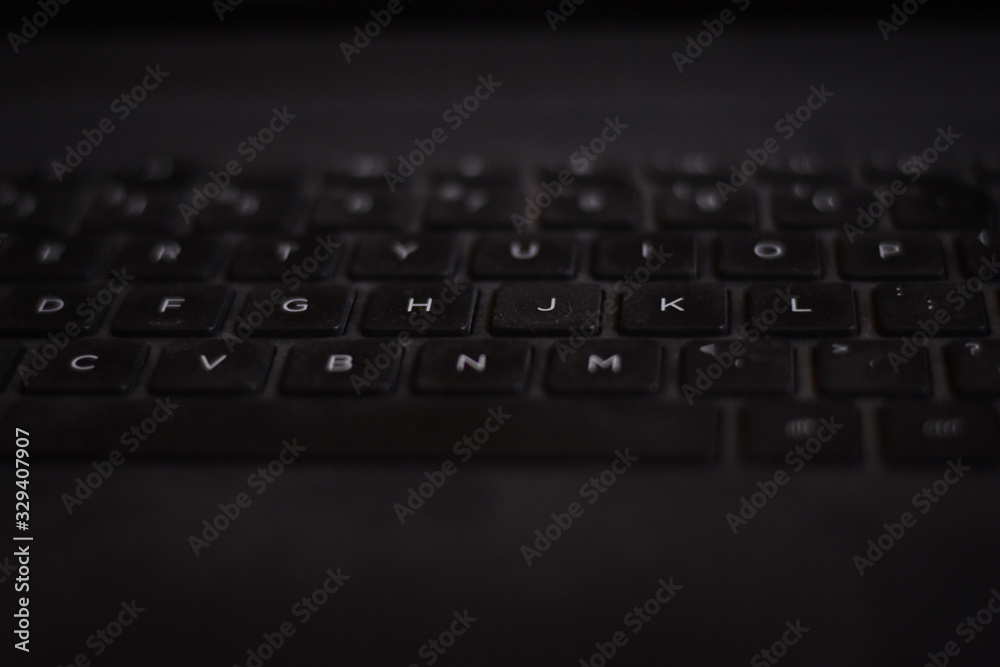 closeup of a laptop keyboard and the laptop on black background  