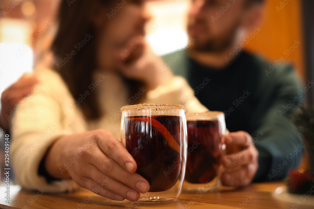 Couple with tasty mulled wine at table in cafe, closeup. Winter vacation