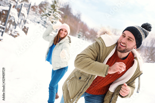 Happy couple playing snowballs outdoors. Winter vacation