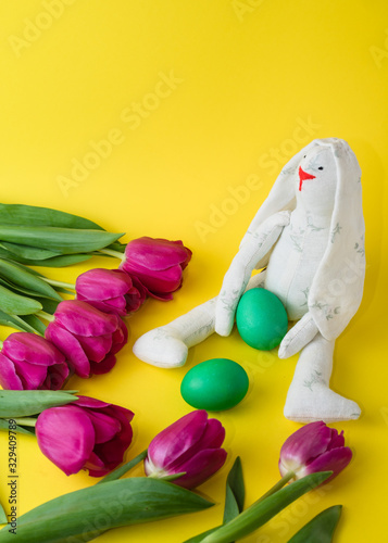 Easter concept. tulips, easter bunny and colored eggs on a yellow background