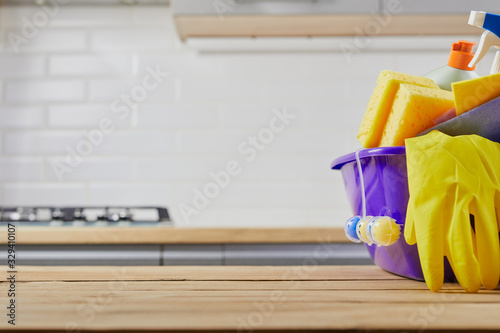 Cleaning supplies : sponge, bottle , glove, spray on table and gray kitchen background, close up