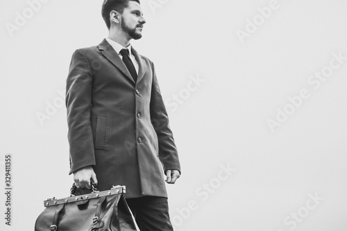 Fototapeta Portrait of a thirty years old bearded guy, in a business style, with a leather bag in his hands