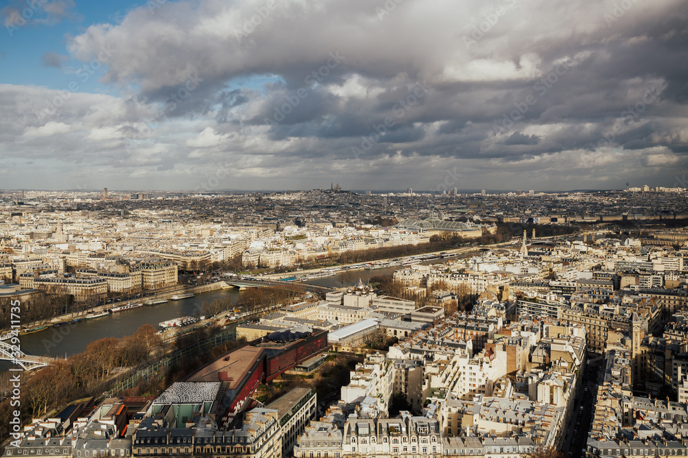 Panorama of Paris, France taken from Eiffel Tower. The river Seine with clouds on sky in winter sunny day. Landscape panoramic view from Eiffel tower and Seine river during the sunny day in Paris. Panorama of Paris, France taken from Eiffel Tower. The river Seine with clouds on sky in winter sunny day. Landscape panoramic view from Eiffel tower and Seine river during the sunny day in Paris.