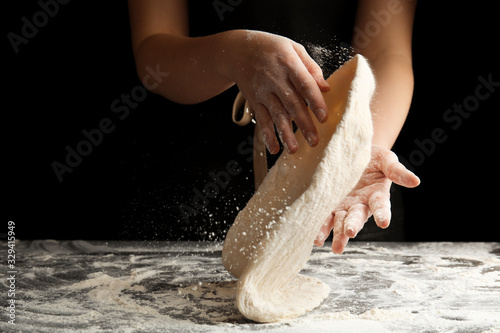 Woman kneading dough for pizza at grey table, closeup