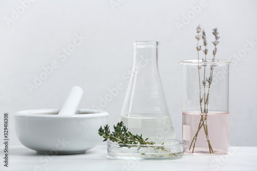 Ingredients for herbal cosmetic products and  laboratory glassware on white table
