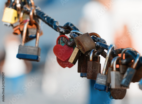  Closeup of a padlock hanging on chain link of the bridge / Fence
