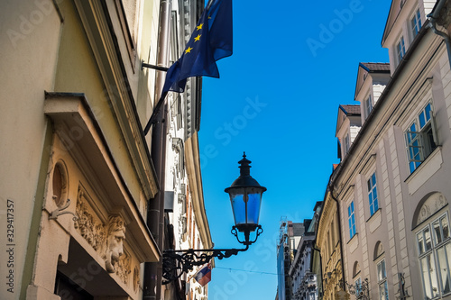 Aged Slovak houses in Old Town of Bratislava city, Slovakia. Metal carved lantern under blue sky