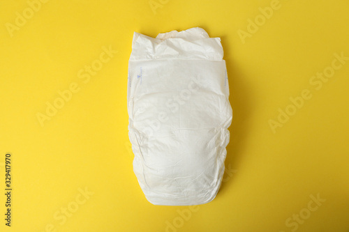 Baby diaper on yellow background, top view
