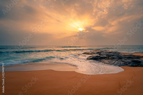 Rocks and stones at the ocean coast under a beautiful sunset sky with clouds on Sri Lanka island.