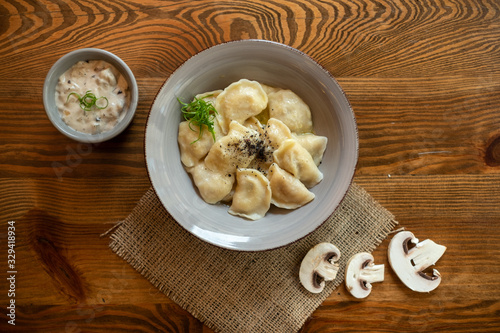 Dumplings with mushrooms  in ceramic plate on wooden table