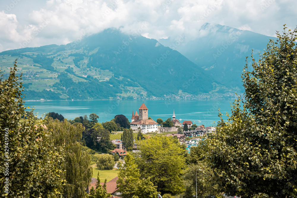 View from one of the railway stations of the Swiss railway. Far away mountains in clouds and haze. Panoramic view of small town on the shores of Lake.