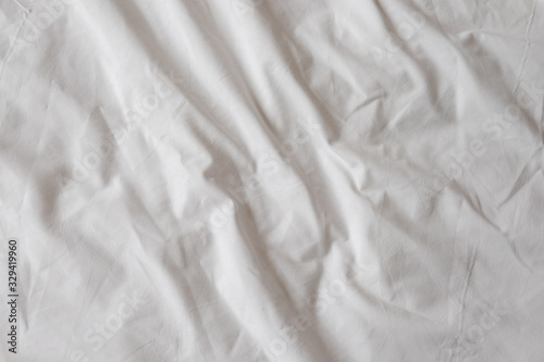Background of white rumpled sheets. Bed linen with wrinkles in d