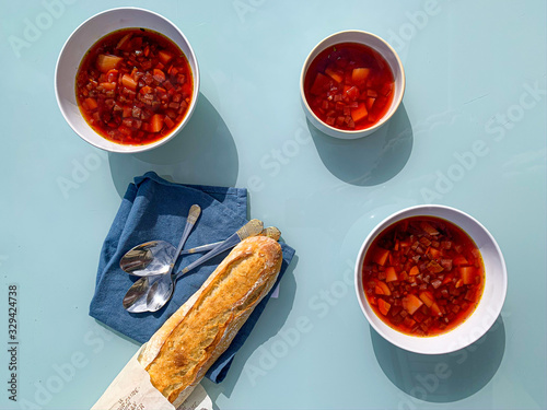 Foto Three bowls of borsch russian soup on a blue table