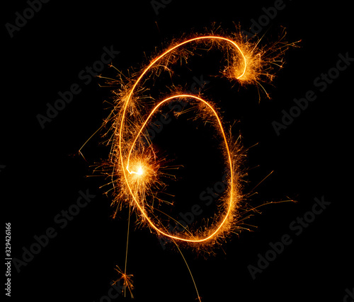number six written with a sparkler on a black background