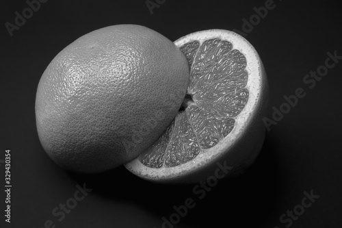 Grapefruit cut in half dark monochrome backdrop, copy space. Fruitarianism, vegetarian or vegan food: fresh and ripe citrus fruit in low key colors photo