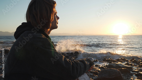 Young caucasian boy meets the dawn at sea shore