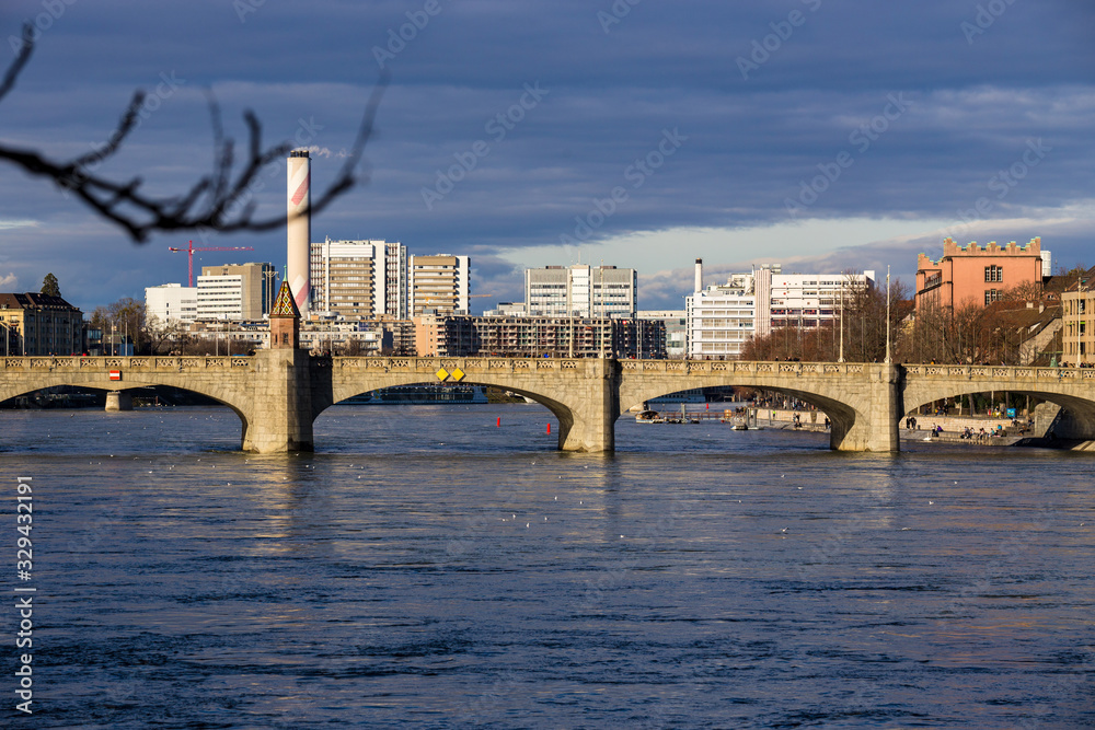 Fototapeta premium View on Basel city and river Rhine, Switzerland. Heritage, beautiful. Swiss city Basel in sunny weather in winter. View of the embankment and the river Rhine, in which people walk and relax