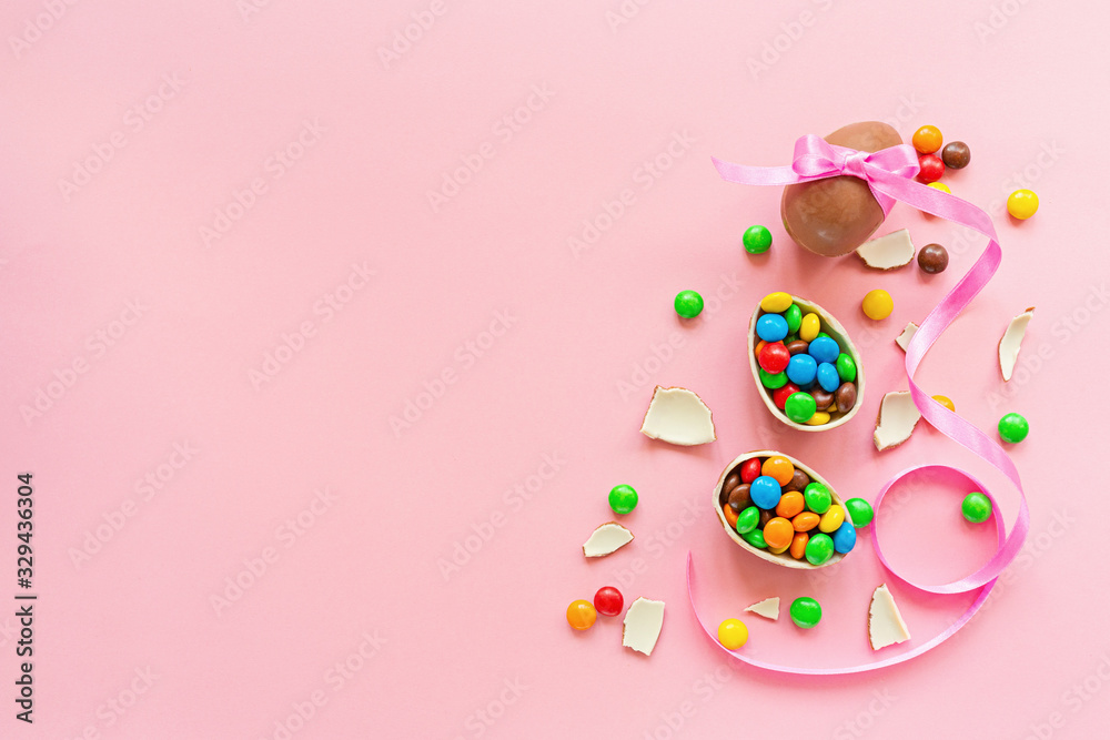 Chocolate Easter eggs and colorful candies on pastel pink paper background. flat lay, top view, overhead, copy space, template, mockup