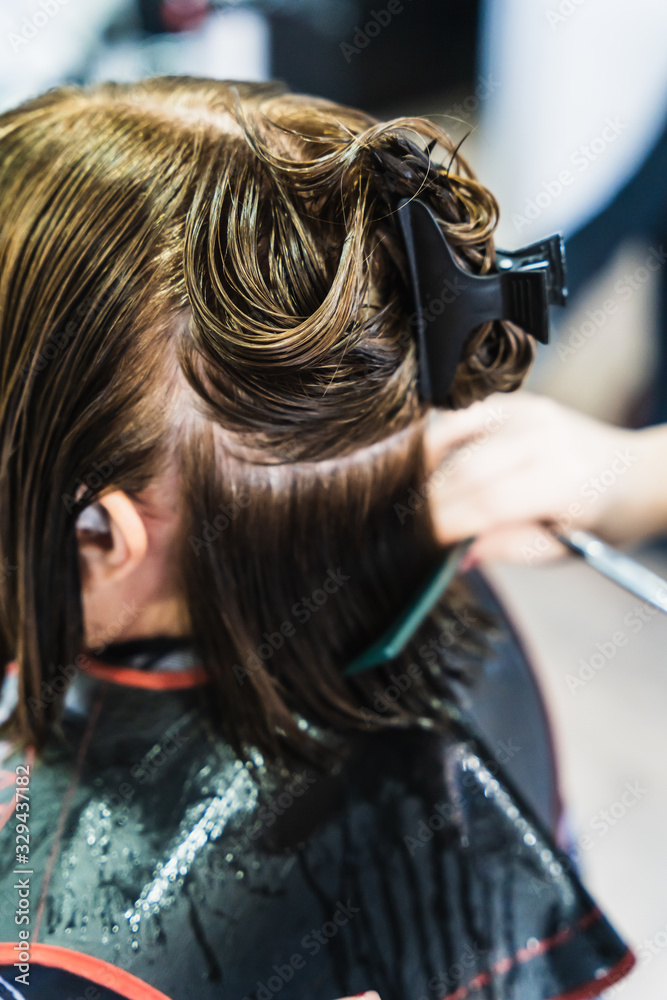 Fototapeta premium A vertical closeup shot of a hairdresser cutting a woman's short hair in a beauty salon