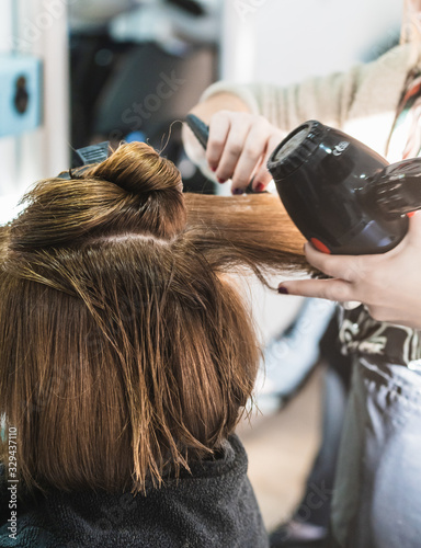 A closeup shot of a hairdresser blow drying a woman's short hair in a beauty salon