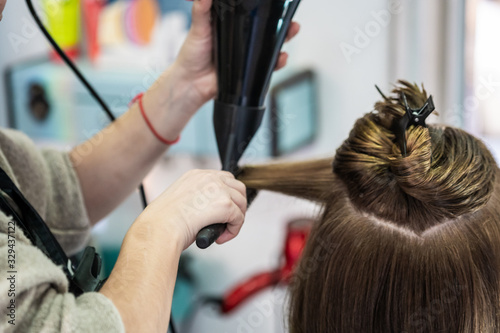 A closeup shot of a hairdresser blow drying a woman's short hair in a beauty salon