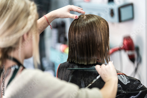 A vertical closeup shot of a hairdresser cutting a woman's short hair in a beauty salon