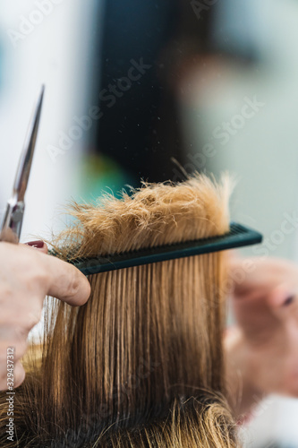 A vertical closeup shot of a hairdresser cutting a woman's short hair in a beauty salon