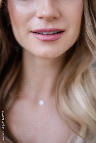 A close up portrait of the pink lips of a beautiful blonde girl with a clean face, without problem-free skin and professional nude makeup. Shining smile with white teeth. Photo without retouching