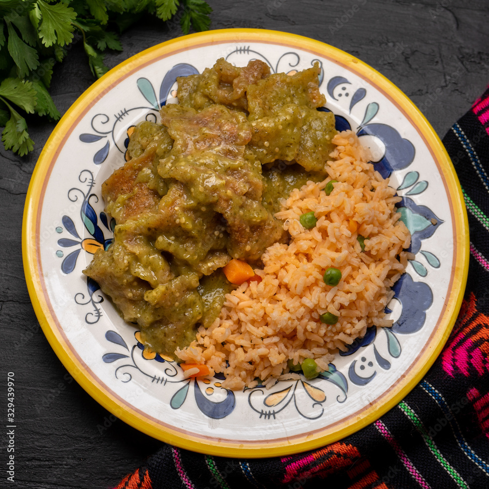 Mexican pork chicharron with green sauce and rice on dark background Mexican pork chicharron with green sauce and rice on dark background
