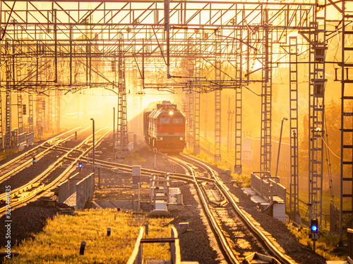Freight train in the yellow rays of the setting sun. Railroad with many tracks