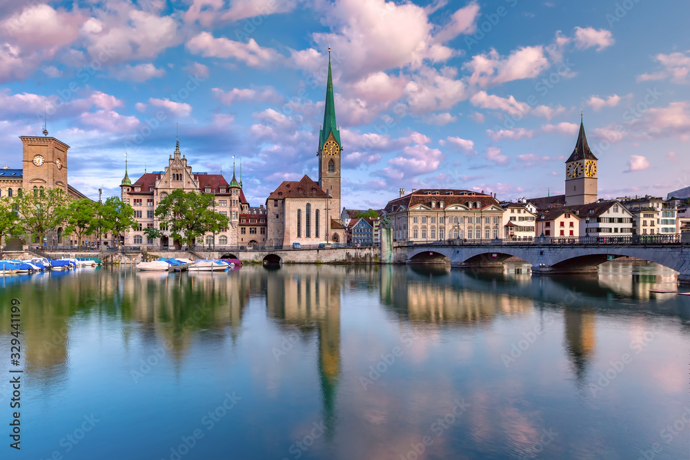 Famous Fraumunster and St Peter church with reflections in river Limmat at sunrise in Old Town of Zurich, the largest city in Switzerland