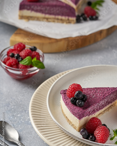 raw vegan double-layer cake with black currant on a light gray background under a concrete texture. Healthy eating, delicious dessert without baking