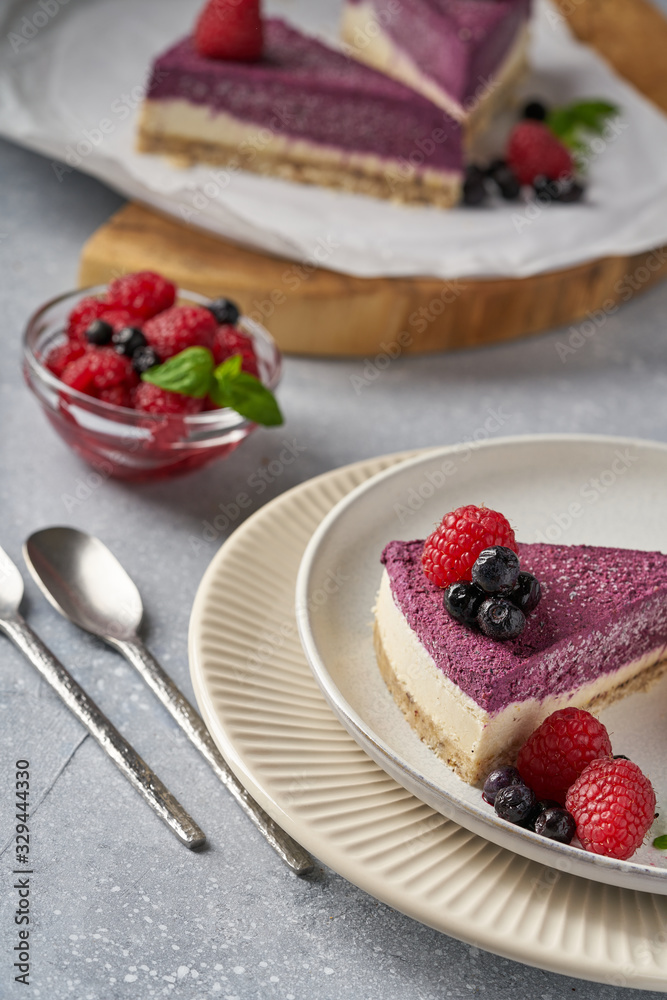 raw vegan double-layer cake with black currant on a light gray background under a concrete texture. Healthy eating, delicious dessert without baking raw vegan double-layer cake with black currant on a light gray background under a concrete texture. Healthy eating, delicious dessert without baking