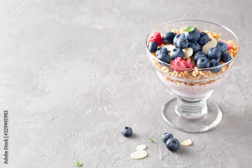 Breakfast. Cereal muesli with yogurt, blueberries, raspberries, almonds and honey on a light background. Space for text.