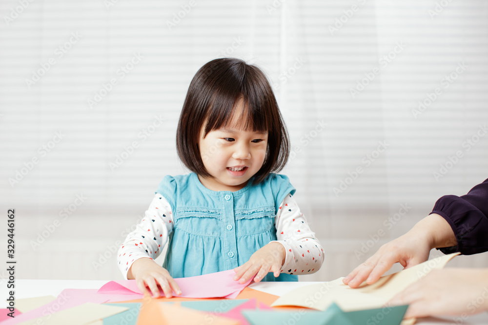 toddler girl learn making Origami at home against white background toddler girl learn making Origami at home against white background