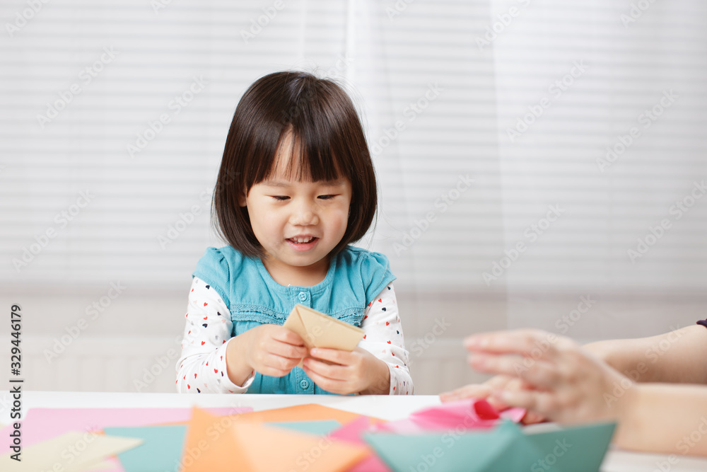 toddler girl learn making Origami at home against white background toddler girl learn making Origami at home against white background