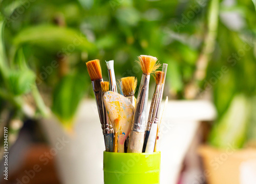 Different Paint Brushes In A green Cup.