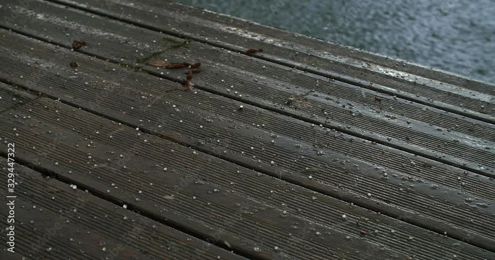 hail falls on an old wooden pontoon and creates ripples in the lake hail falls on an old wooden pontoon and creates ripples in the lake