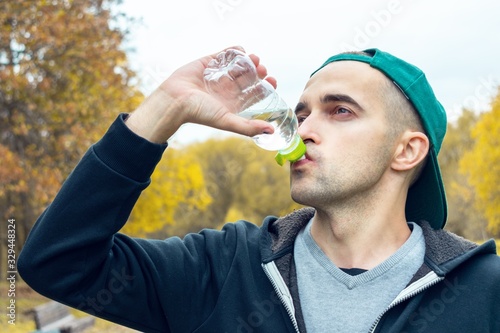 Concept of sports, training and active lifestyle. Guy drinking water after morning jog, close-up