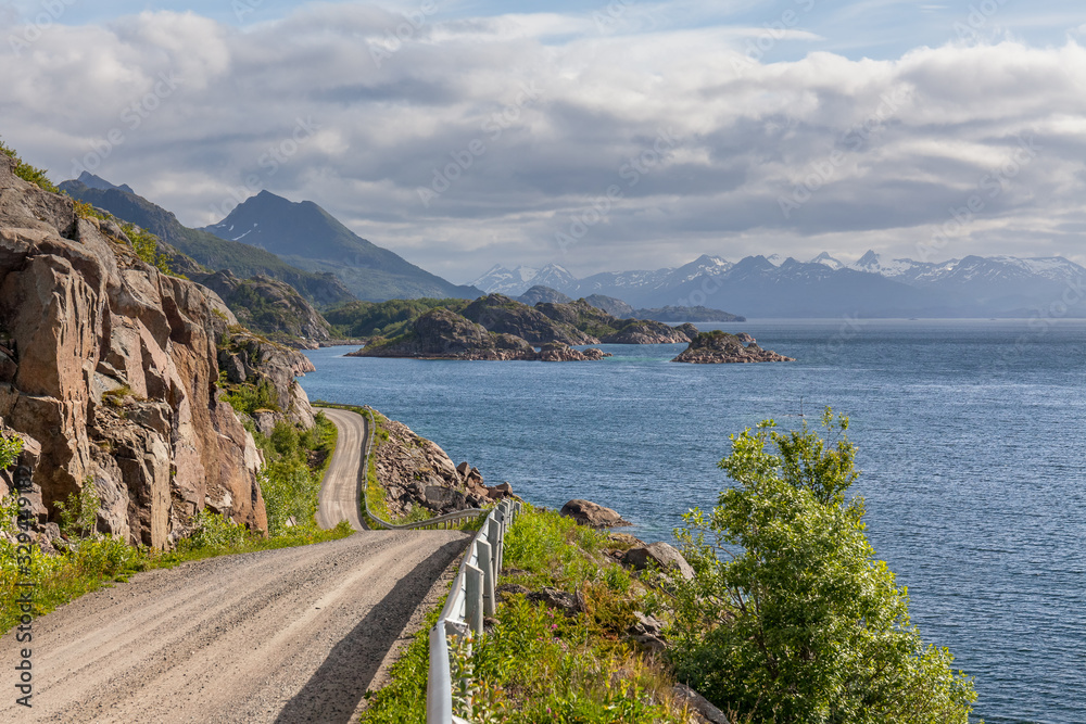 road is meandering between blue fjord and moss mountains in the extreme north of Norway. selective focus