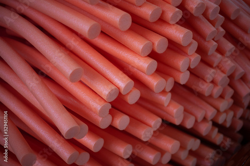 Abstract background of paralon tubes. Texture of red paralon cylinders. Technological picture of cut sausages from inorganic materials. Modern implementation of a minimalistic background. photo