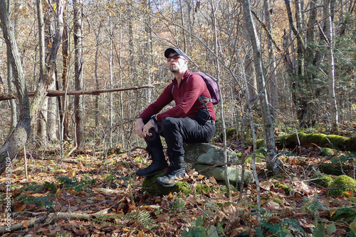 Hiker resting on rock in forest